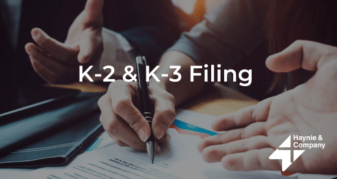 Hands discussing K-2 & K-3 tax filing documents with Haynie branding.