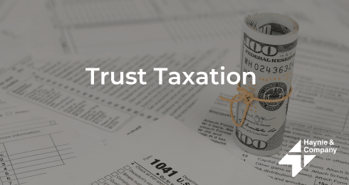 Trust Taxation text over tax forms and rolled dollar bills, Haynie logo visible.