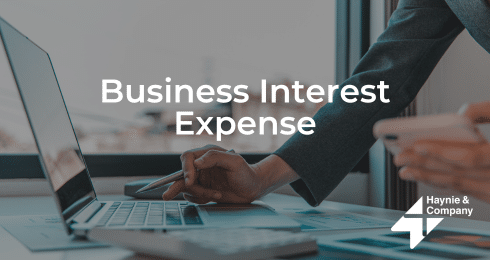 Business interest expense concept with Haynie logo and a woman using a laptop and phone.