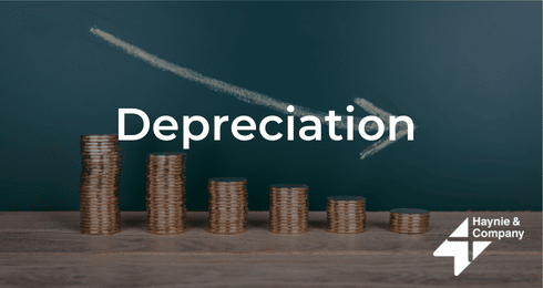 Stacked coins representing depreciation with an arrow pointing downward.