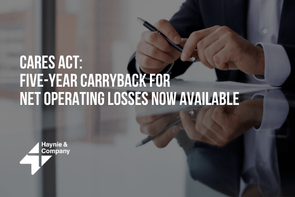 CARES Act information on five-year carryback for net operating losses, person holding a pen at a desk.