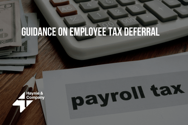 Payroll tax guidance document, calculator, and currency on desk.