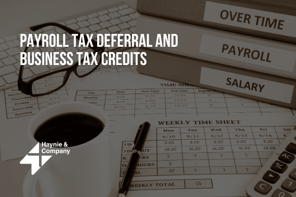 Payroll tax deferral, business tax credits theme with glasses, binders, and calculator on an office desk.