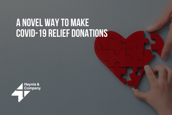 Hands assembling a red heart puzzle with text on COVID-19 relief donations.