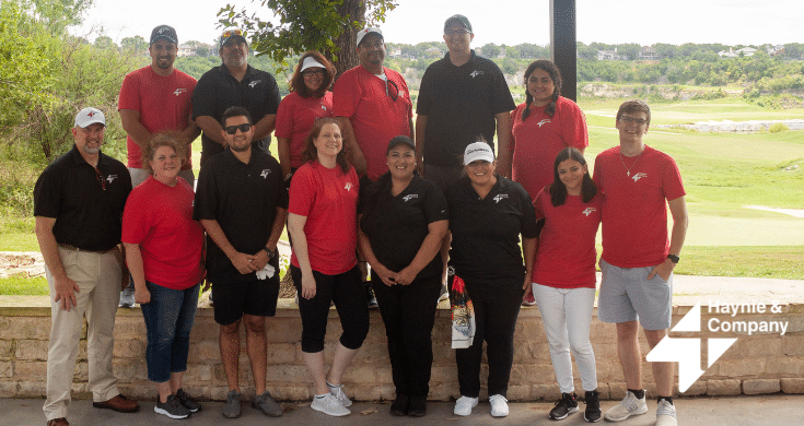 Team photo of Haynie staff outdoors in matching red and black shirts.
