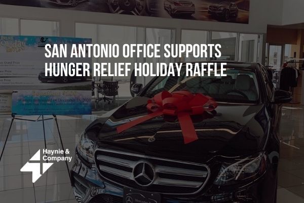 Black car with red bow in office showroom supporting holiday raffle for hunger relief.
