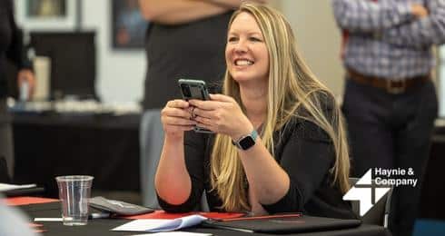 A woman smiling and using a phone at a Haynie event.