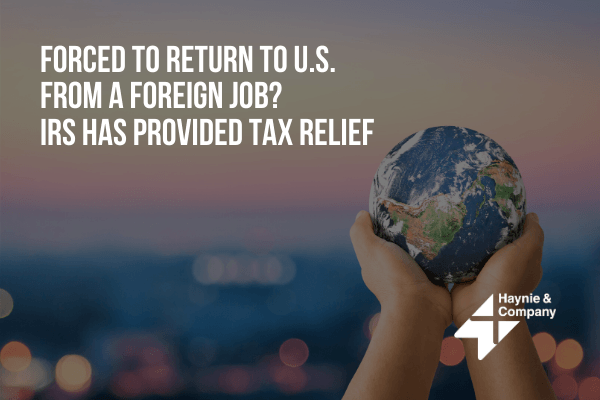 Hands holding a small globe with text about IRS tax relief for those returning to the U.S. from foreign jobs.