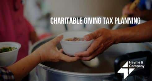 Hand serving food with text Charitable Giving Tax Planning and Haynie logo in background.