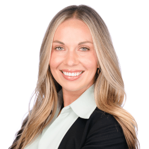 Smiling woman with long blond hair in professional attire against a white background.