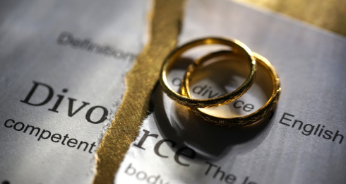 Two gold rings on a torn divorce document, symbolizing separation.