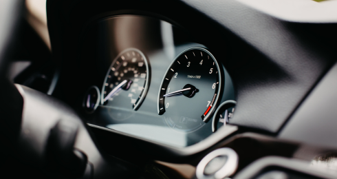 Close-up of car dashboard with speedometer and tachometer in focus.